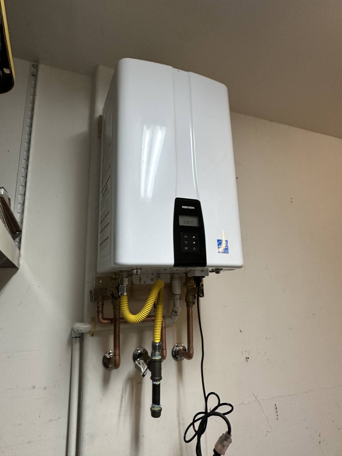 Completed Navien tankless water heater installed by Poly Plumbing in a Lincoln, CA home, with copper water lines and a yellow gas line